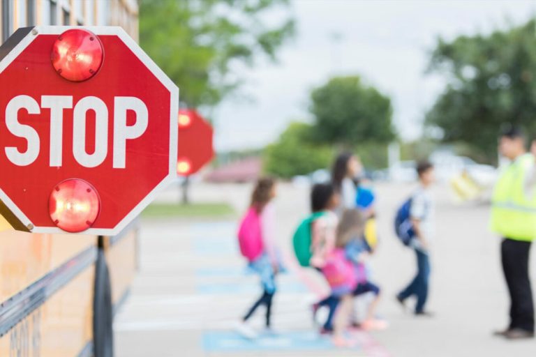 School Bus stop-arm down and flashing while students cross the street.