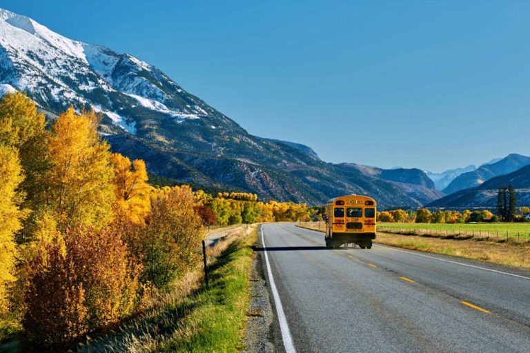 School bus on highway in Colorado Rocky Mountains at autumn, USA. Mount Sopris landscape.