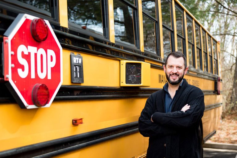 Jean Souliere standing by a school bus.