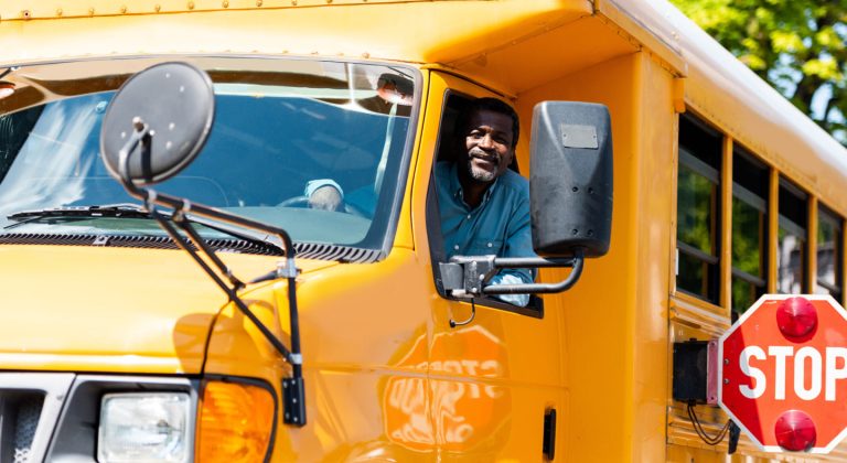 School bus driver leaning out of the window.